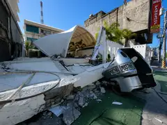A collapsed building resting on a car after the June 2026 Mindanao earthquake